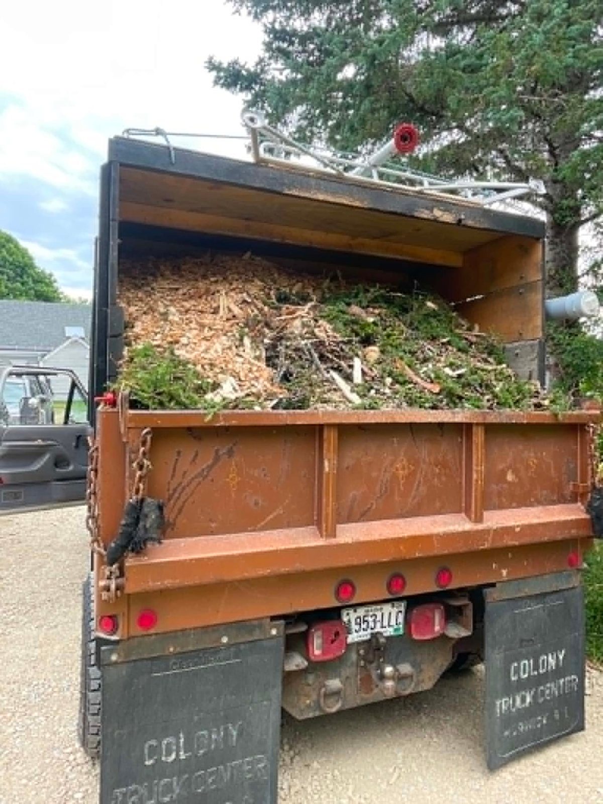 Black Dog Tree Service truck loaded with brush and wood chips at the end of a job